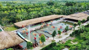 Un resort con estructuras de techo de paja, una piscina y un entorno natural.