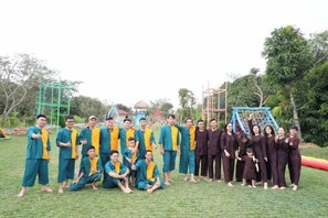 A group of people in a grassy area with playground equipment in the background. - Cantho Eco Resort (Can Tho)