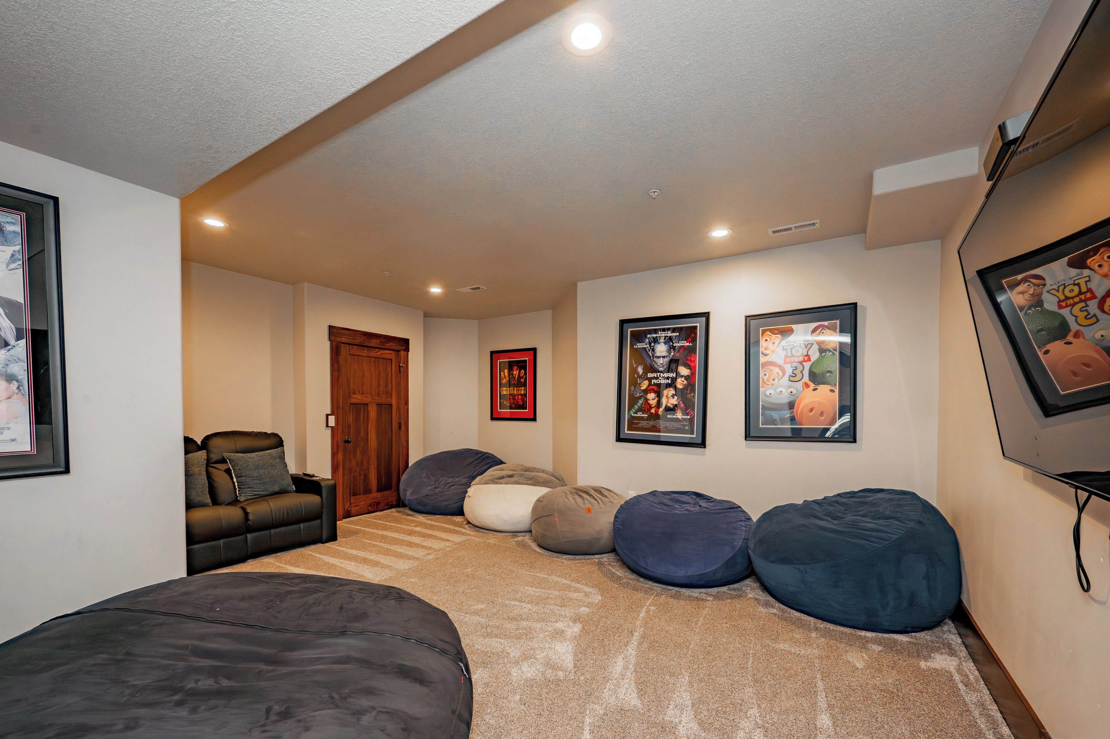 A cozy room with a sofa, bean bags, and framed posters on the wall.