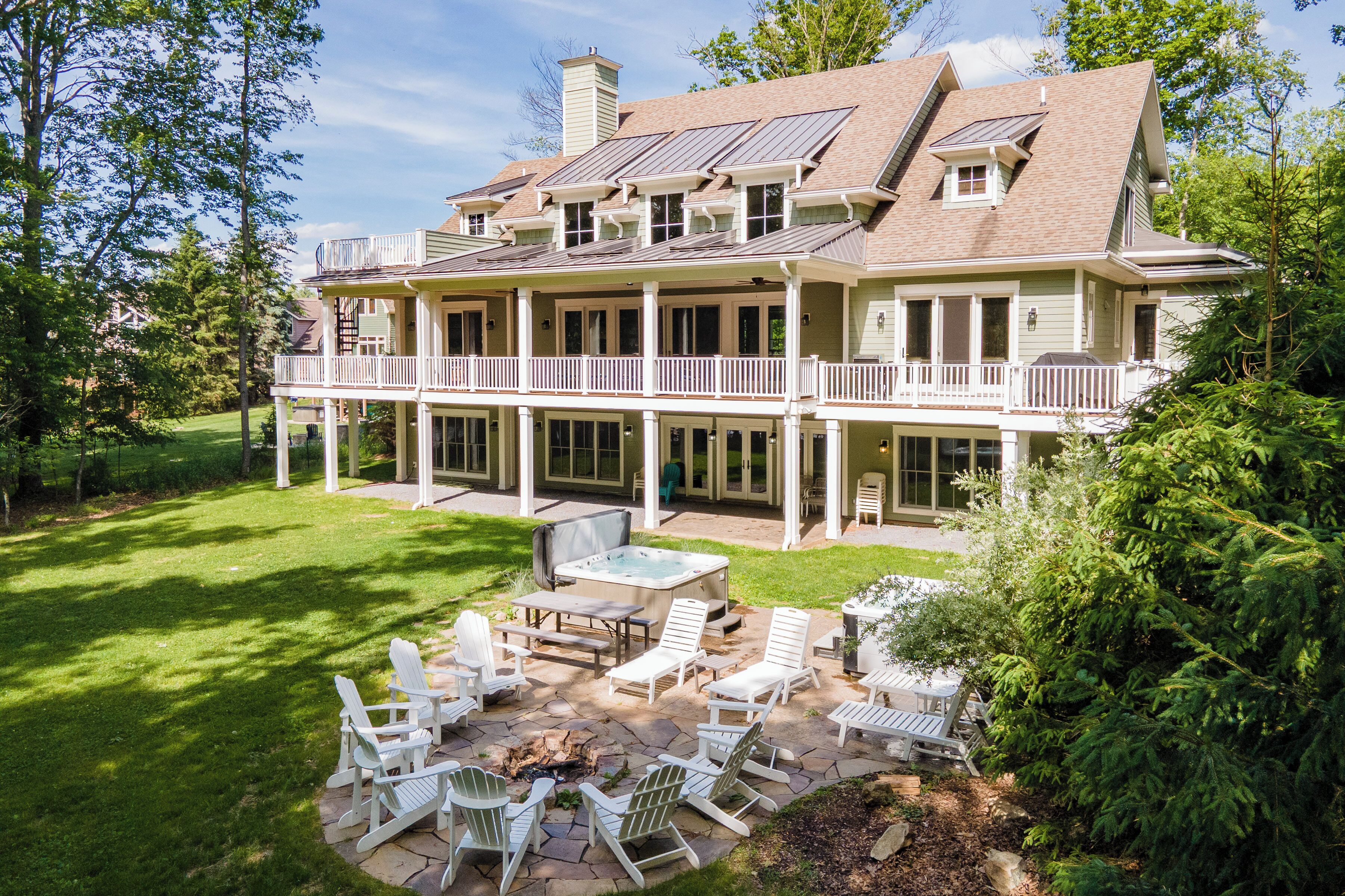 A large two-story house with a covered patio area featuring outdoor furniture and a fire pit.
