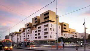 A modern building with multiple floors and a tram passing by.