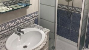 A bathroom with a glass-enclosed shower, a sink with a marble countertop, and a mirror above the sink. - Pension San Vicente (San Vicente de la Sonsierra)