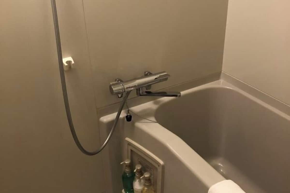 Een badkamer met een bad, een douche en een handdoekrek.