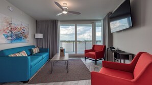 Uma sala de estar moderna com um sofá azul, uma poltrona vermelha e uma televisão de tela plana.