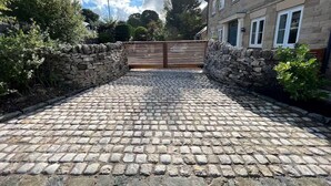 Un vialetto in pietra che conduce a un cancello con muri di pietra ai lati.