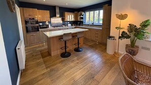 Una cucina moderna con mobili in legno, un'isola centrale con sgabelli e una finestra che offre luce naturale.