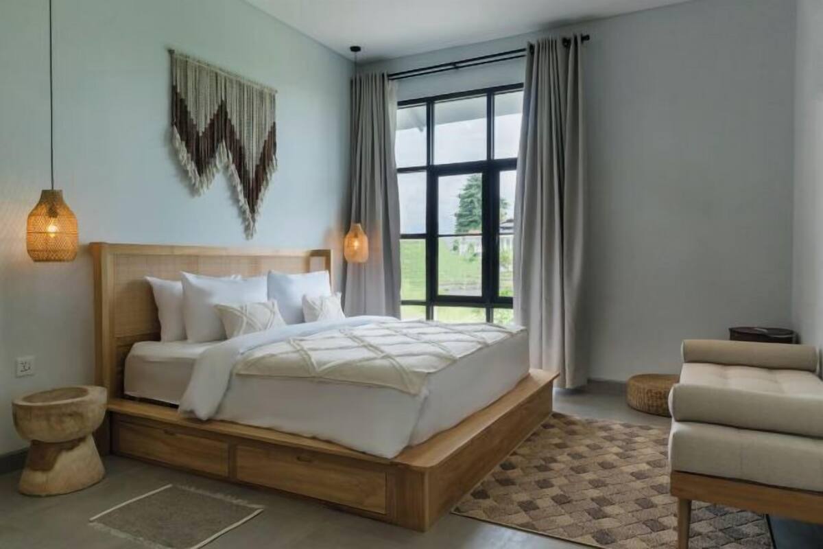 Een slaapkamer met een houten bed, twee bedlampen, uitzicht op de omgeving en een klein zitgedeelte.