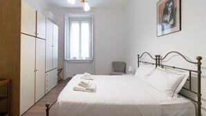 Ein Schlafzimmer mit Bett, Kleiderschrank, Stuhl und Fenster.