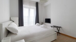 A modern hotel room with a large bed, a flat-screen TV mounted on the wall, and a small table with a tray. - Italianway Easy - Scarampo 41 (Milano)