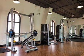 A gym with weightlifting equipment, large windows, and a high ceiling. - CityHouse - Atelier Thao Dien (Ho Chi Minh City)