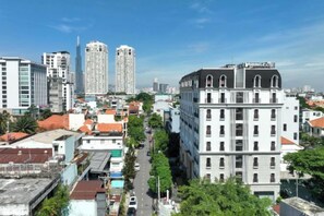 A cityscape with a prominent white building with a flat roof and multiple windows, surrounded by other buildings and a clear sky. - CityHouse - Atelier Thao Dien (Ho Chi Minh City)