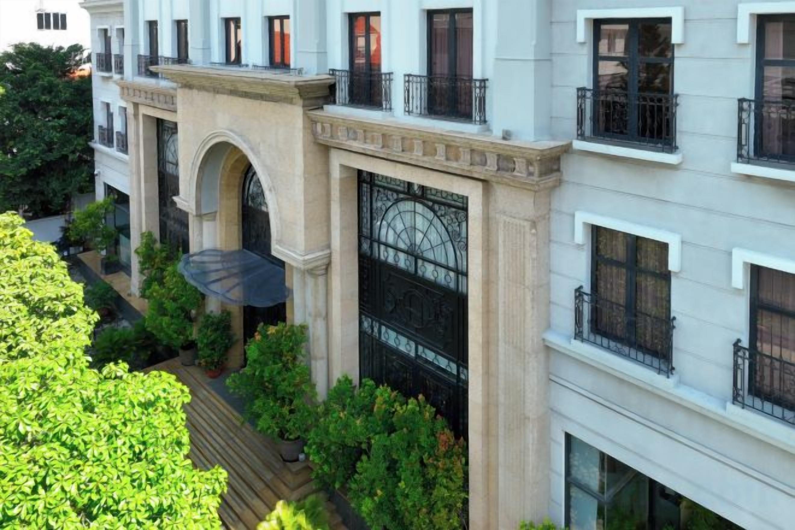 Un edificio de varios pisos con balcones, ventanas amplias y una entrada central en arco.