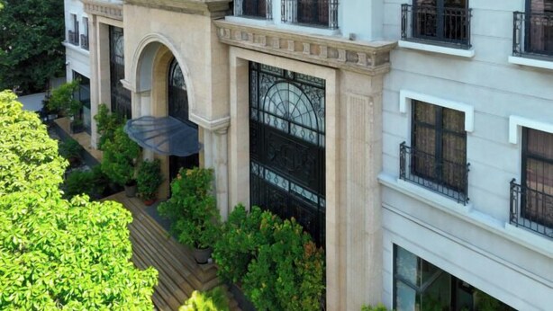 A multi-story building with a central courtyard, featuring a large arched entrance and a decorative iron gate. - CityHouse - Atelier Thao Dien (Ho Chi Minh City)
