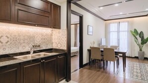 A kitchen with dark wooden cabinets, a marble backsplash, and a dining area with a table and chairs. - CityHouse - Atelier Thao Dien (Ho Chi Minh City)