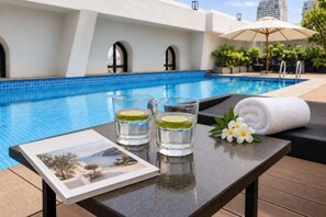 A poolside setting with a table, glasses of water, a towel, and a flower arrangement. - CityHouse - Atelier Thao Dien (Ho Chi Minh City)