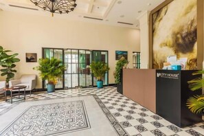 A hotel lobby with a reception desk, seating area, and potted plants. - CityHouse - Atelier Thao Dien (Ho Chi Minh City)