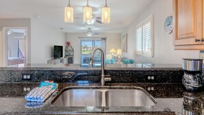 A modern kitchen with granite countertops, stainless steel sink, and pendant lights. - Seastars IV (Fort Myers Beach)