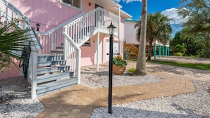 A pink house with a white staircase leading to a covered porch. - Seastars IV (Fort Myers Beach)