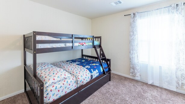 A bunk bed with a ladder, a window with sheer curtains, and a ceiling light. - The Nest at Hackmatack (Houston)