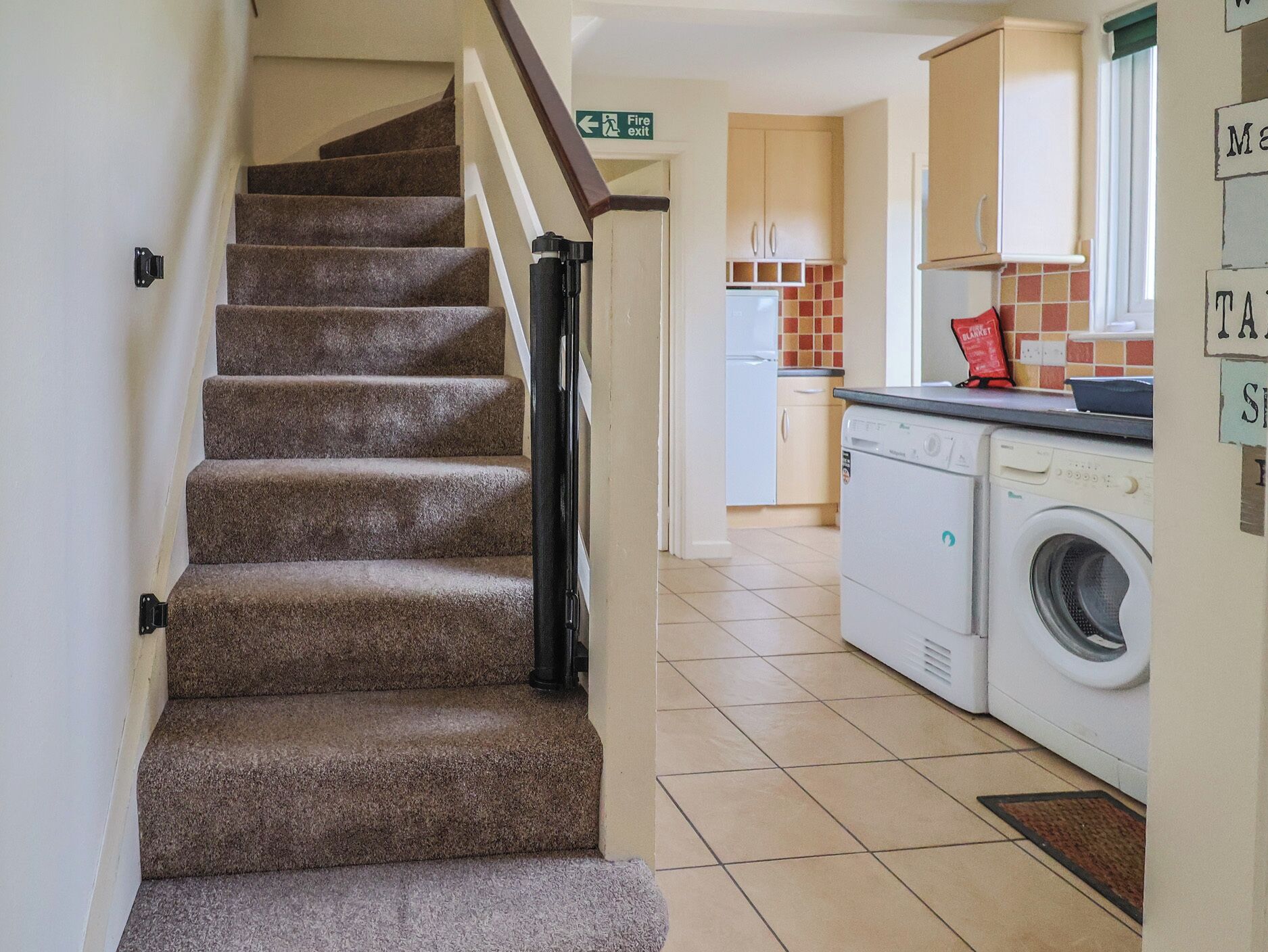 A staircase leading to a kitchen area with a washing machine and a refrigerator.