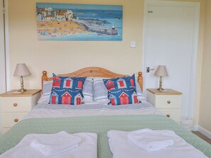 A bed with two pillows, a green bedspread, and two folded towels. - Court House Farmhouse (Bridport)