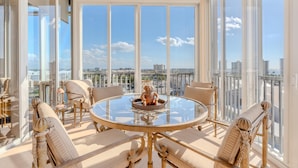 A spacious balcony with a round glass table, wicker chairs, and a decorative sculpture. - Palm Harbor #704 (Fort Myers Beach)