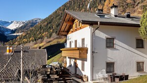Un refugi de muntanya amb un balcó, bigues de fusta i vista a una muntanya nevada.