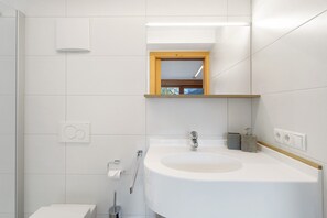 Casa de banho moderna com uma pia grande, um espelho e uma janela.