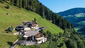 Une propriété située sur une colline, comprenant plusieurs bâtiments, une route et une forêt environnante.