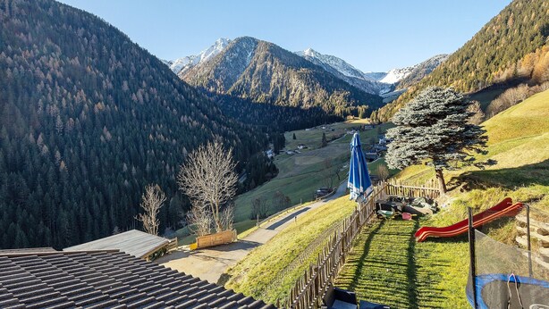 Un paysage montagneux avec une piste de ski, une clôture en bois et un ciel dégagé.