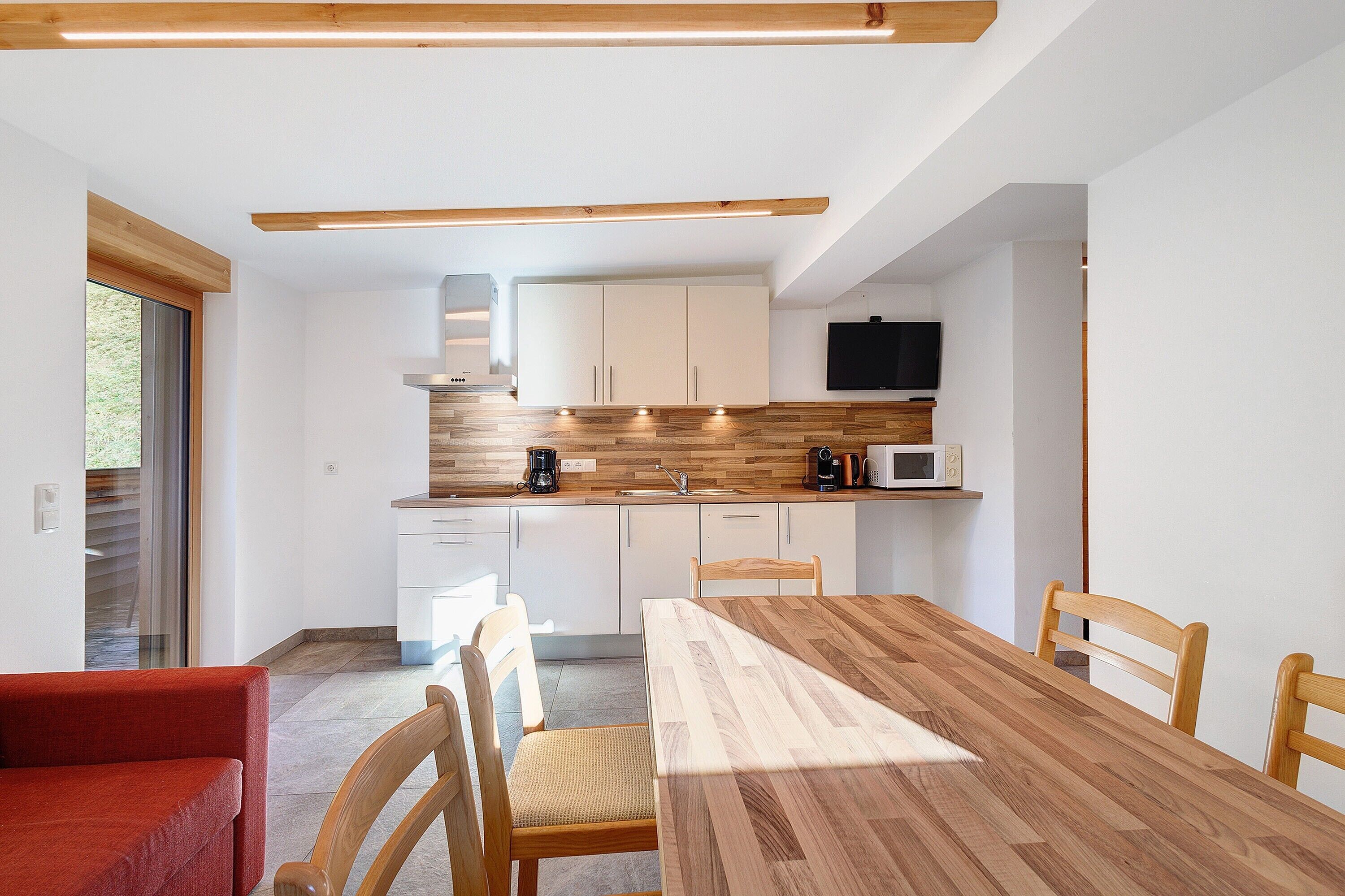 Une cuisine moderne avec des armoires blanches, un plan de travail en bois et un four à micro-ondes encastré.