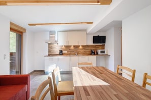 Une cuisine moderne avec des armoires blanches, un plan de travail en bois et un four à micro-ondes encastré.