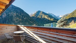 Une terrasse en bois avec une table et des chaises, offrant une vue sur un paysage montagneux.