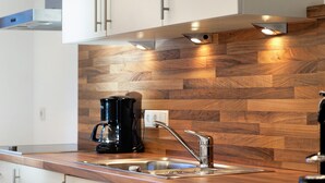 Une cuisine moderne avec un revêtement mural en bois, un évier en acier inoxydable et une machine à café.