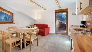Une cuisine moderne avec des meubles en bois, un coin repas avec une table et des chaises en bois, et un canapé rouge.