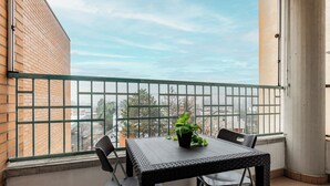 A balcony with a table and chairs, a potted plant, and a view of the cityscape. - Bedetti Modern Flat by Wonderful Italy (Bologna)