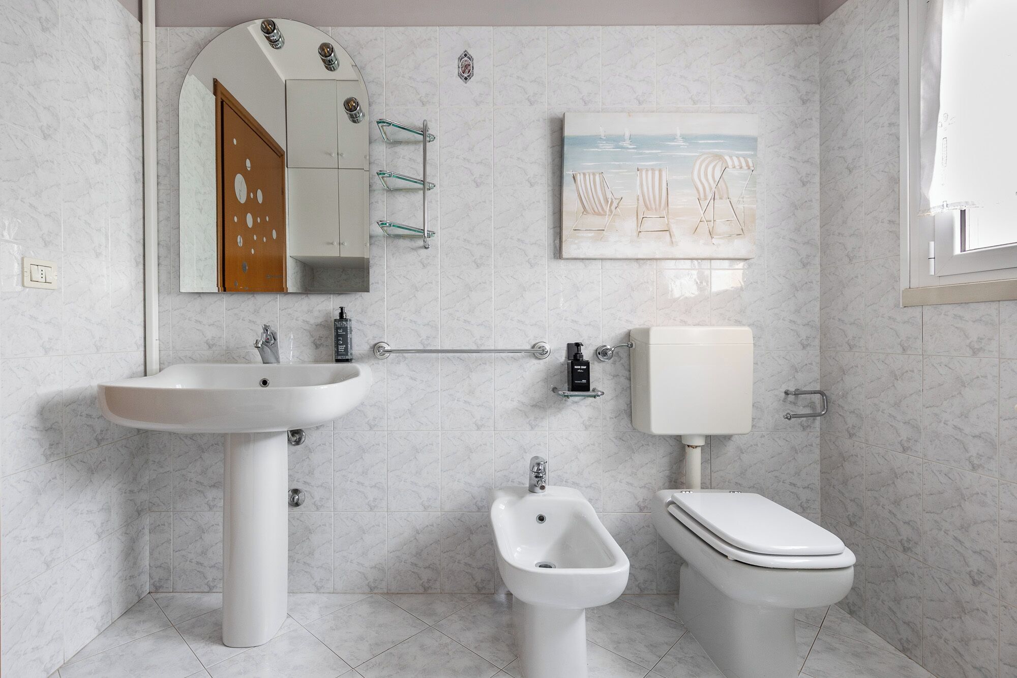 A bathroom with a sink, bidet, toilet, and a mirror.