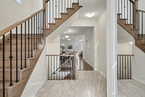 A staircase with wooden steps and black railings leading to an upper floor. - Willow Nest - 5 Beds, 2.5 Baths, 3 Park, Backyard, Thermea Spa (Whitby)