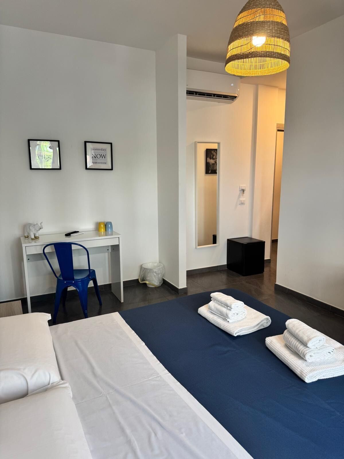 A hotel room with a bed, a desk, a chair, and a large mirror.