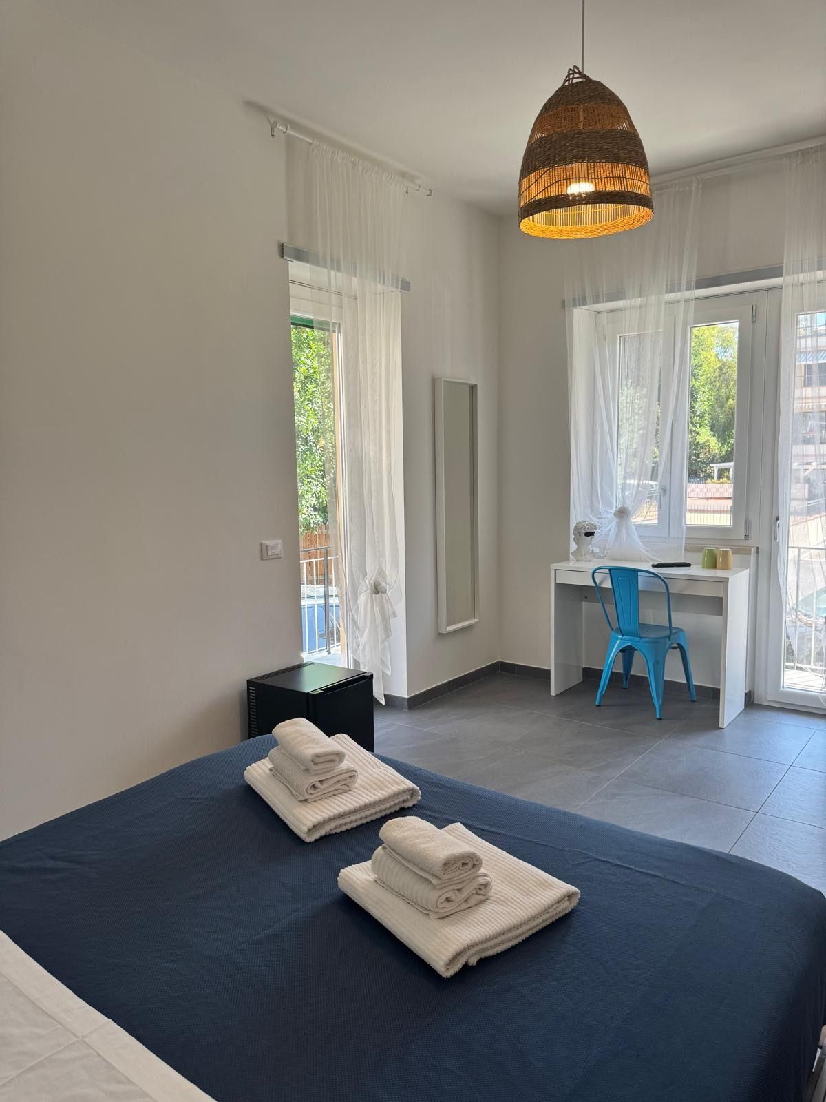 Una habitación de hotel con cama, escritorio, silla y lámpara colgante.