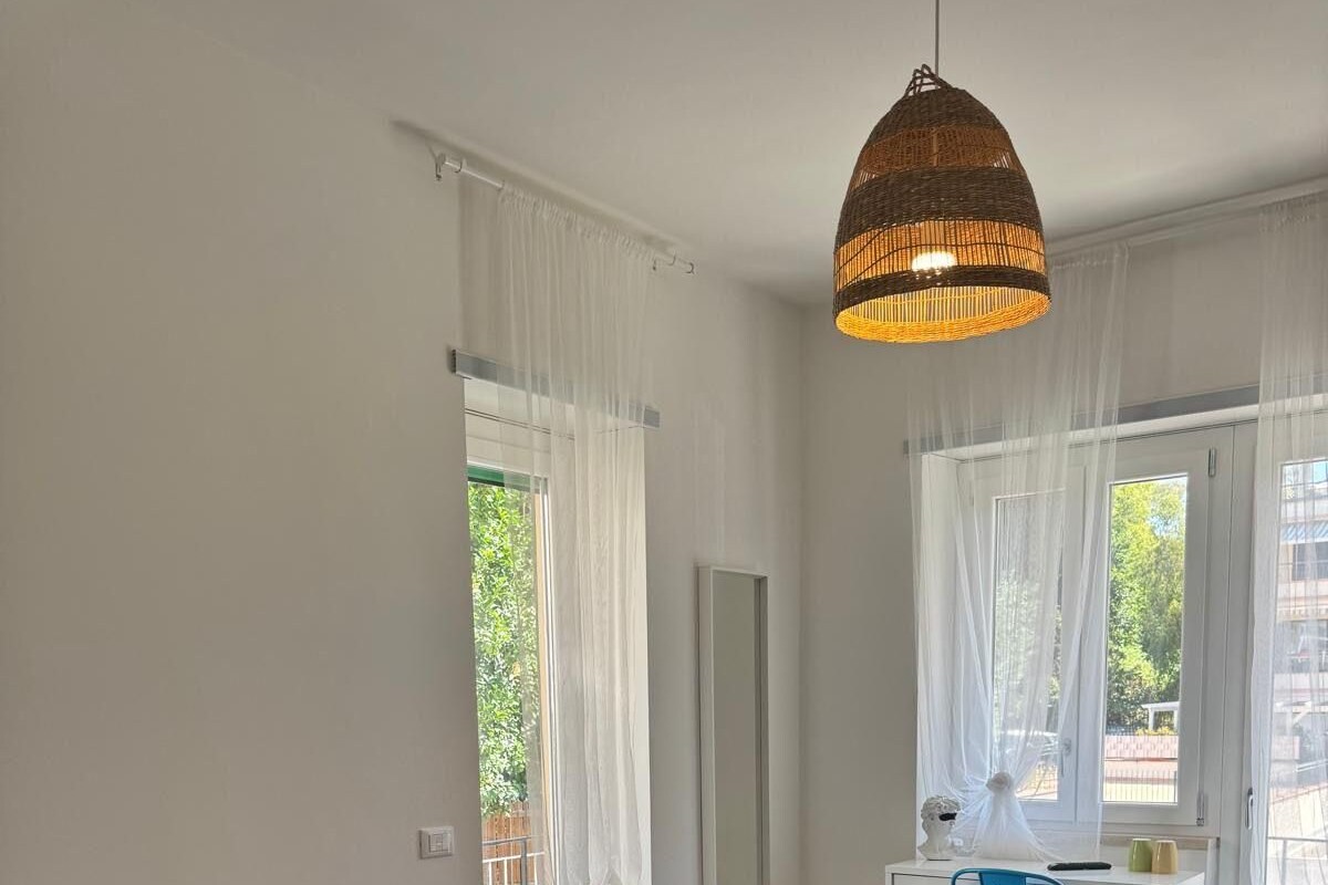 A hotel room with a bed, a desk, a chair, and a hanging light fixture.