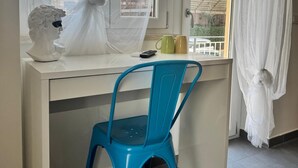 A room with a white desk, a blue chair, a bust sculpture, and a window with sheer curtains. - Sapore Di Mare Riviera (Gaeta)