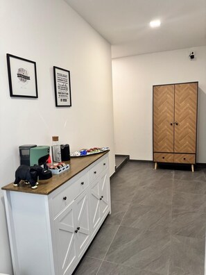 Een moderne keuken met een houten aanrecht, witte kasten en een garderobe met een herringbone patroon.