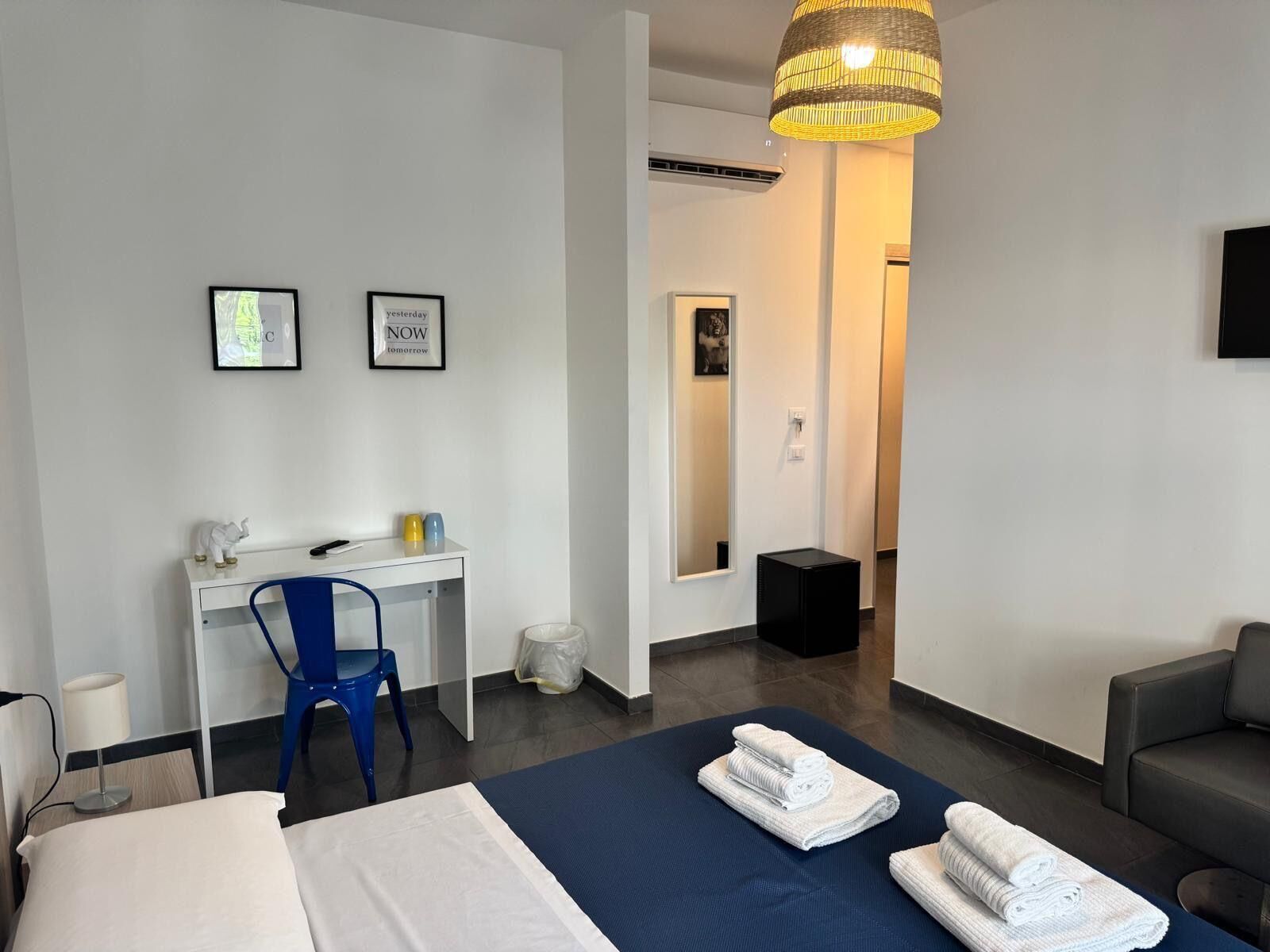Una habitación de hotel moderna con cama, escritorio, silla, sofá y un espejo grande.