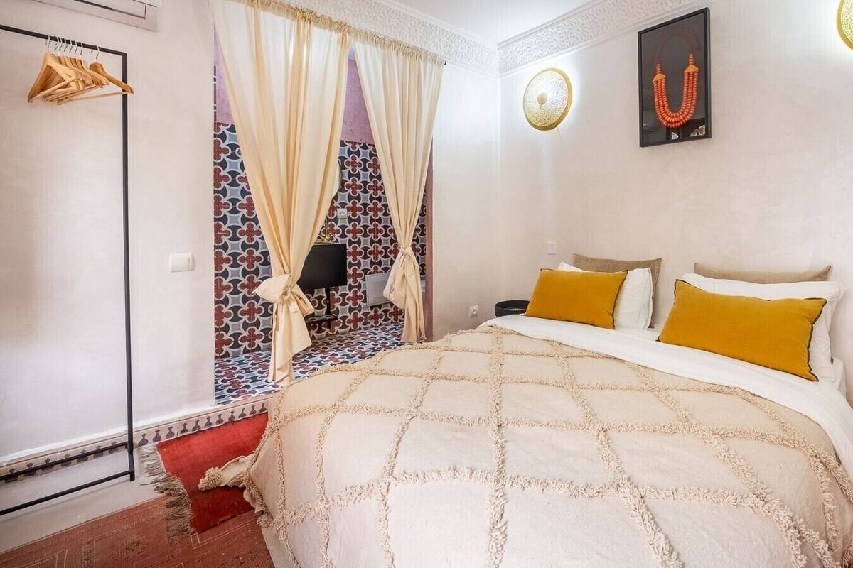 A bedroom with a large bed, a wardrobe, a television, and a decorative wall piece.