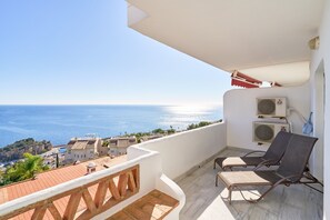 Un balcón con dos sillones de descanso, vista al mar y dos unidades de aire acondicionado.
