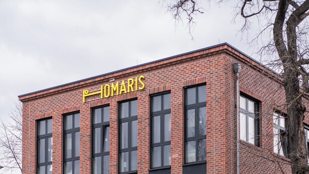 Un bâtiment en briques rouges avec l’inscription « IOMARIS » sur la façade.