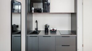 Une cuisine moderne équipée d’un four à micro-ondes, d’une machine à café et de tasses posées sur le comptoir.