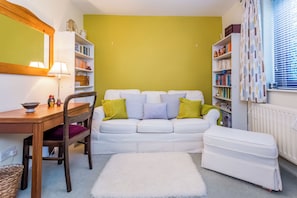 A cozy living room with a white sofa, a small table, and a bookshelf. - Toast Stays - Elgin Escape (Darlington)