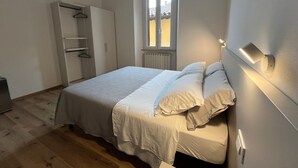 A bedroom with a bed, a wardrobe, a radiator, and a window. - Pertichetti Living room 2 (Foligno)